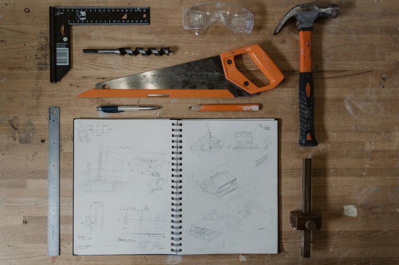 Flat lay of workshop tools and a sketchbook on a bench
